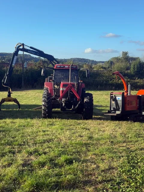 The HGM Contracting fleet parked in a field: pickup and trailer, tractor with timber crane and grapple, wood chipper and Land Rover